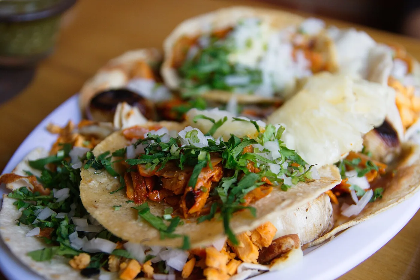 A plate of tacos al pastor topped with onion and cilantro. The photo was not taken at a Roswell restaurant.